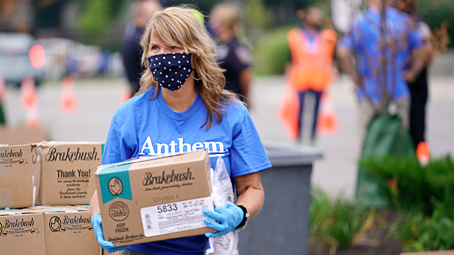 Woman wearing a face mask and gloves holding a box