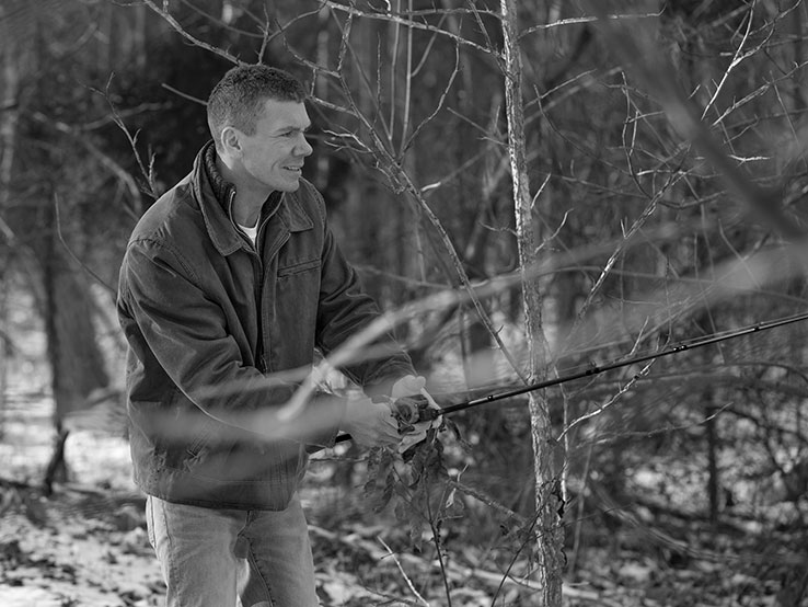 Man holding a fishing rod surrounded by trees