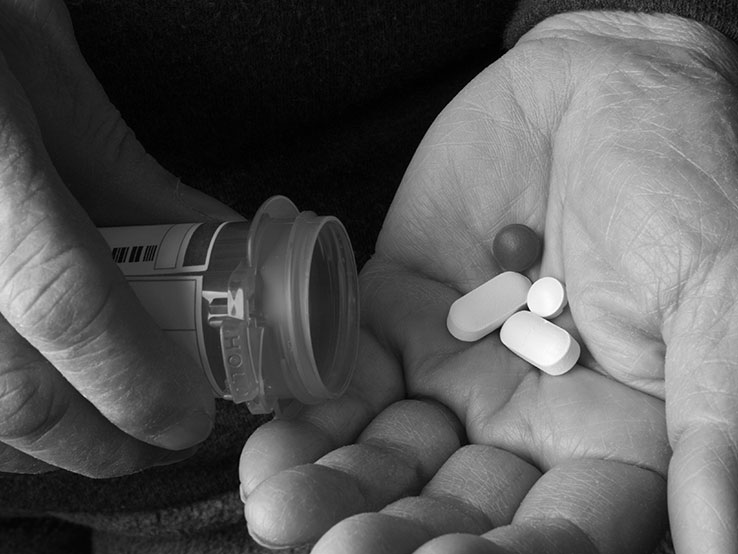 Two hands holding a pill container and pills