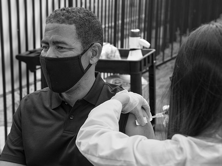 Nurse vaccinating a man with a face mask